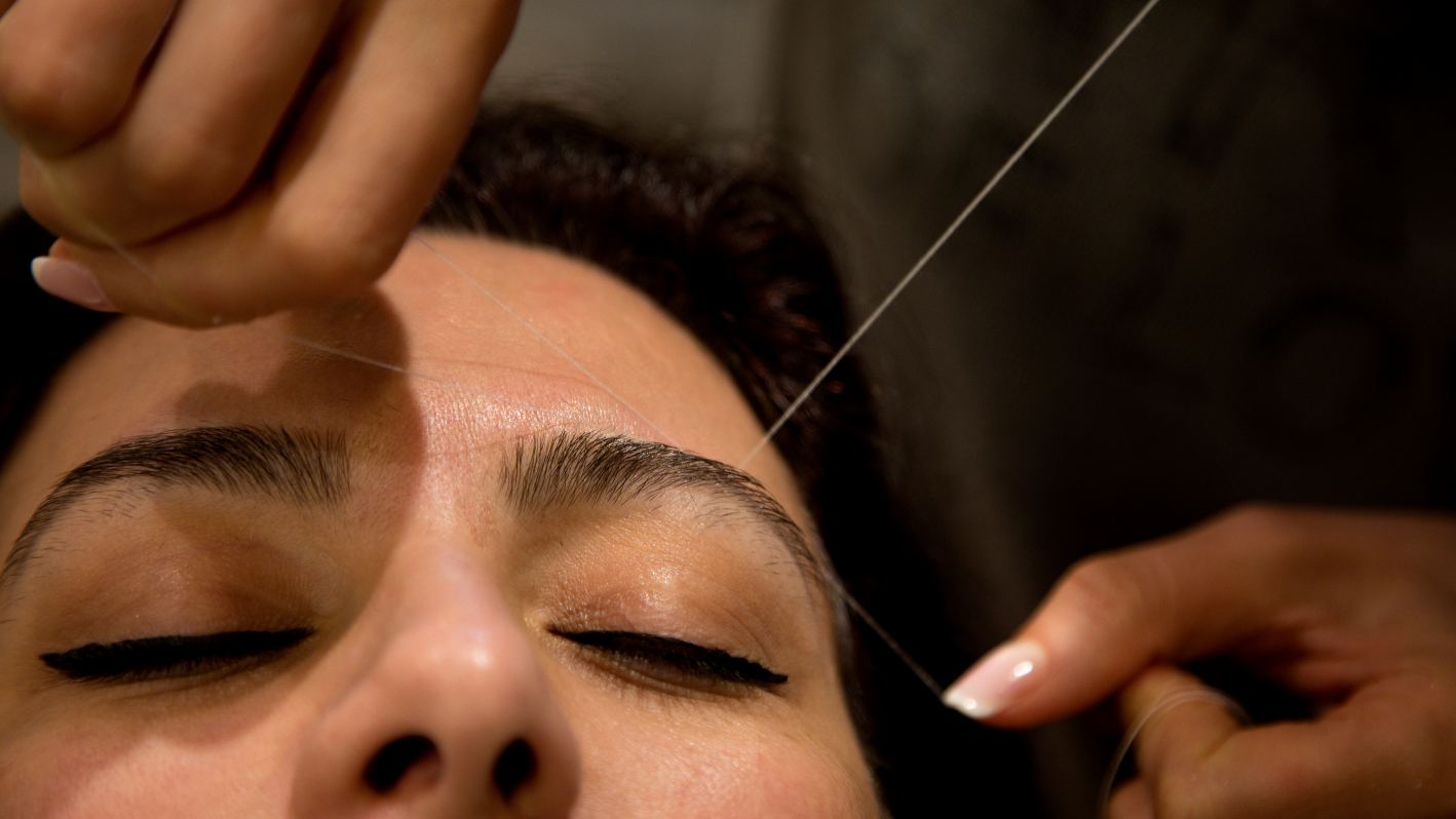 Eyebrow threading procedure, close-up of person's face during beauty treatment